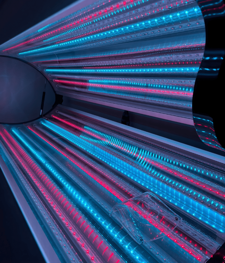 Person inside a glowing LED-lit tunnel with vibrant blue and pink lights.